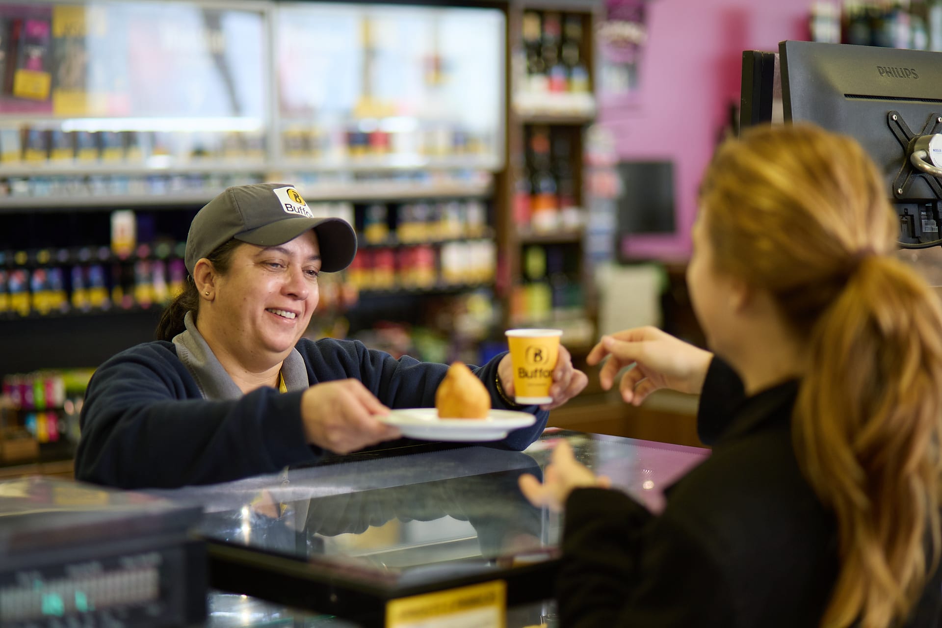 Atendente servindo cliente no balcão da conveniência B MIX